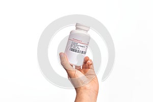 Hand of caucasian young man holding bottle of  pills over isolated white background