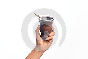 Hand of caucasian young man holding cup of mate infusion beverage over isolated white background