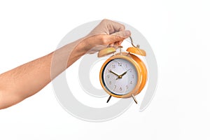 Hand of caucasian young man holding yellow vintage alarm clock over isolated white background