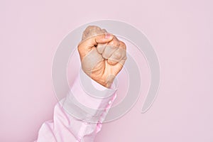 Hand of caucasian young man showing fingers over isolated pink background doing protest and revolution gesture, fist expressing