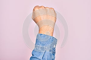 Hand of caucasian young man showing fingers over isolated pink background doing protest and revolution gesture, fist expressing