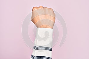 Hand of caucasian young man showing fingers over isolated pink background doing protest and revolution gesture, fist expressing