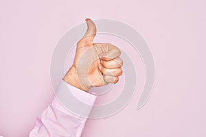 Hand of caucasian young man showing fingers over isolated pink background doing successful approval gesture with thumbs up,