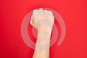 Hand of caucasian young man showing fingers over isolated red background doing protest and revolution gesture, fist expressing