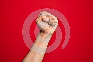Hand of caucasian young man showing fingers over isolated red background doing protest and revolution gesture, fist expressing