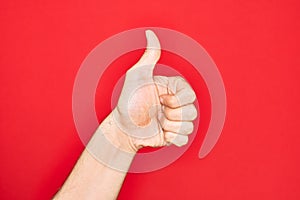 Hand of caucasian young man showing fingers over isolated red background doing successful approval gesture with thumbs up,