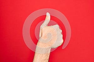 Hand of caucasian young man showing fingers over isolated red background doing successful approval gesture with thumbs up,
