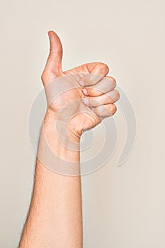 Hand of caucasian young man showing fingers over isolated white background doing successful approval gesture with thumbs up,