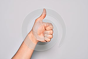 Hand of caucasian young man showing fingers over isolated white background doing successful approval gesture with thumbs up,