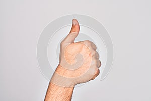 Hand of caucasian young man showing fingers over isolated white background doing successful approval gesture with thumbs up,