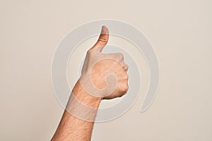 Hand of caucasian young man showing fingers over isolated white background doing successful approval gesture with thumbs up,