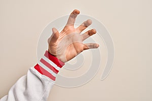 Hand of caucasian young man showing fingers over isolated white background grasping aggressive and scary with fingers, violence