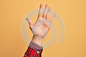 Hand of caucasian young man showing fingers over isolated yellow background counting number 5 showing five fingers