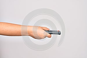 Hand of caucasian young woman changing television channel holding tv remote control over isolated white background