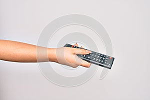 Hand of caucasian young woman changing television channel holding tv remote control over isolated white background