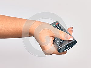 Hand of caucasian young woman changing television channel holding tv remote control over isolated white background