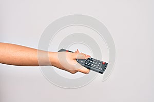 Hand of caucasian young woman changing television channel holding tv remote control over isolated white background