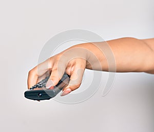 Hand of caucasian young woman changing television channel holding tv remote control over isolated white background