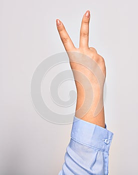 Hand of caucasian young woman doing victory symbol showing number two with streched fingers raised up over isolated white