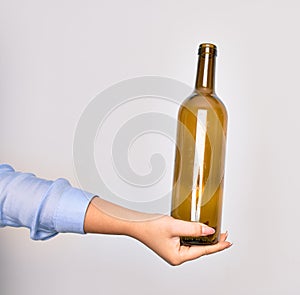 Hand of caucasian young woman holding empty glass botlle of wine over isolated white background