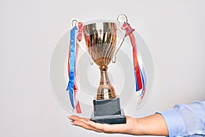 Hand of caucasian young woman holding golden trophy over isolated white background