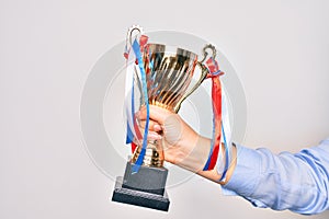 Hand of caucasian young woman holding golden trophy over isolated white background