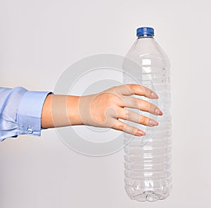 Hand of caucasian young woman holding plastic bottle to recycle over isolated white background