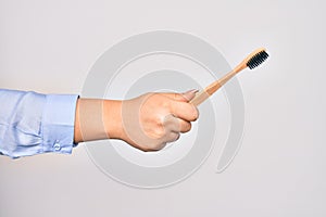 Hand of caucasian young woman holding toothbrush over isolated white background