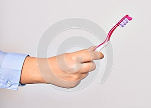 Hand of caucasian young woman holding toothbrush over isolated white background