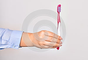 Hand of caucasian young woman holding toothbrush over isolated white background