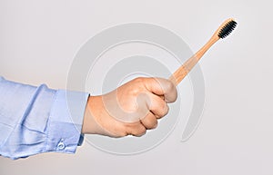 Hand of caucasian young woman holding toothbrush over isolated white background
