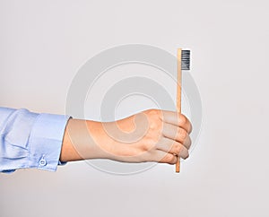 Hand of caucasian young woman holding toothbrush over isolated white background