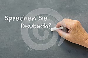 Hand on a chalkboard with the German words Sprechen Sie deutsch