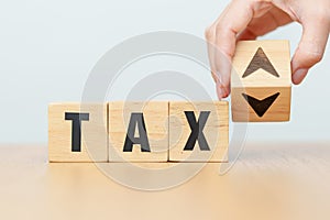 hand change wooden block with TAX text to UP and Down arrow icon. decrease and Increase, Taxpayer, Taxable Income, Tax Filing,