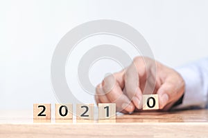 Hand is changing a wooden cube symbolically changes from 2020 to 2021