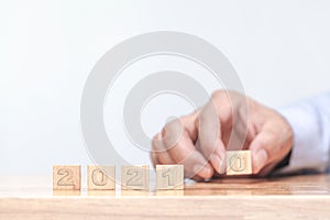 Hand is changing a wooden cube symbolically changes from 2020 to 2021