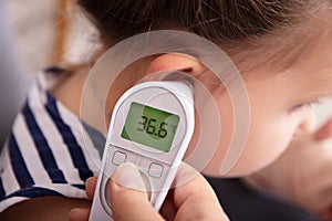 Hand Checking Girl`s Ear With Digital Thermometer