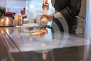 Hand of Chef cooking salmon steak