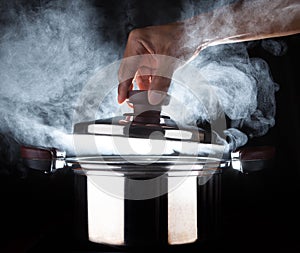 Hand of chef open hot stream pot with beautiful studio lighting