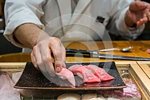 Hand of Chef preparing seafood and raw sliced fish store at Tsukiji sea food market, Japan