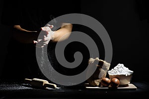 Hand of chef thresh flour with wooden rolling pin and ingredients