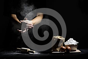 Hand of chef thresh flour with wooden rolling pin and ingredients