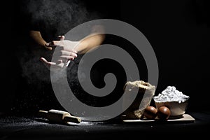 Hand of chef thresh flour with wooden rolling pin and ingredients