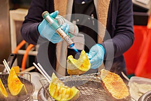Hand of chef cooking and burn slice of cantaloupes and melons on stove photo