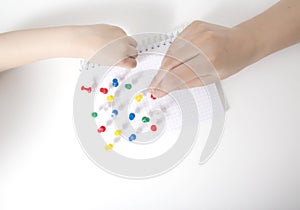 The hand of a child and a doctor sets multi-colored pins in a leaf on a white background. Autism development concept of