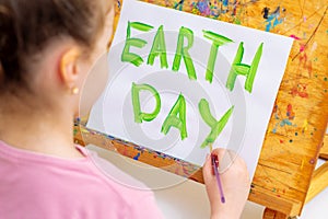 Hand of child drawing words Earth Day