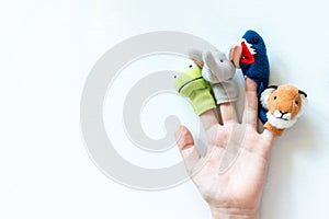 Hand of a child with finger puppets, toys, dolls close up on white background with copy space - playing puppet theatre and