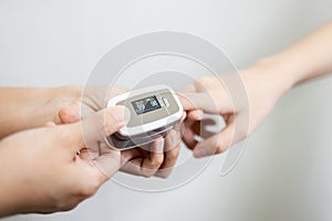 Hand of child girl with fingertip pulse oximeter on finger for examination of the lung disease,checking for Coronavirus COVID-19