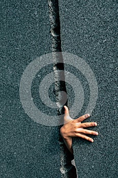 Hand of a child grasps through a narrow gap between two marble walls