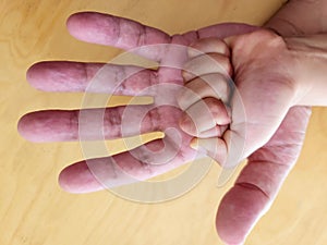 Hand of a child on his father's hand on a wooden background close-up.